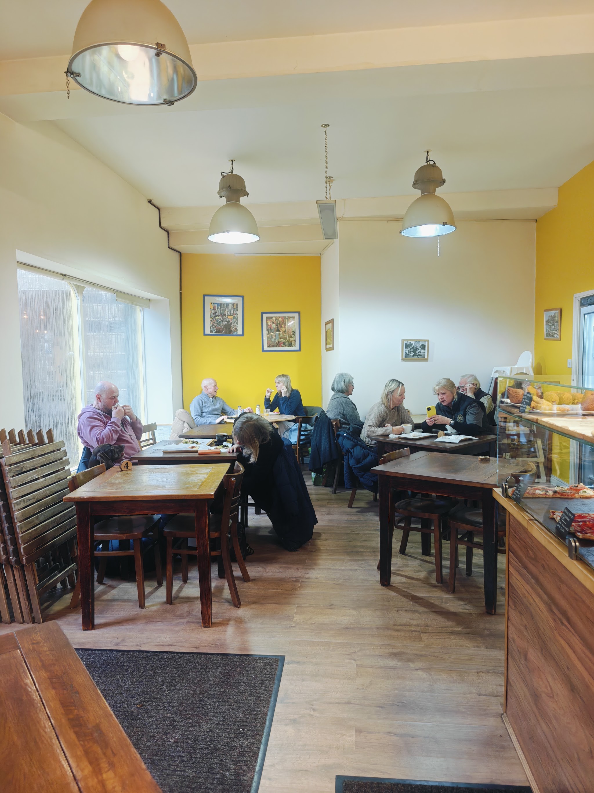 The warm yellow interior of the café with wooden tables and customers enjoying lunch