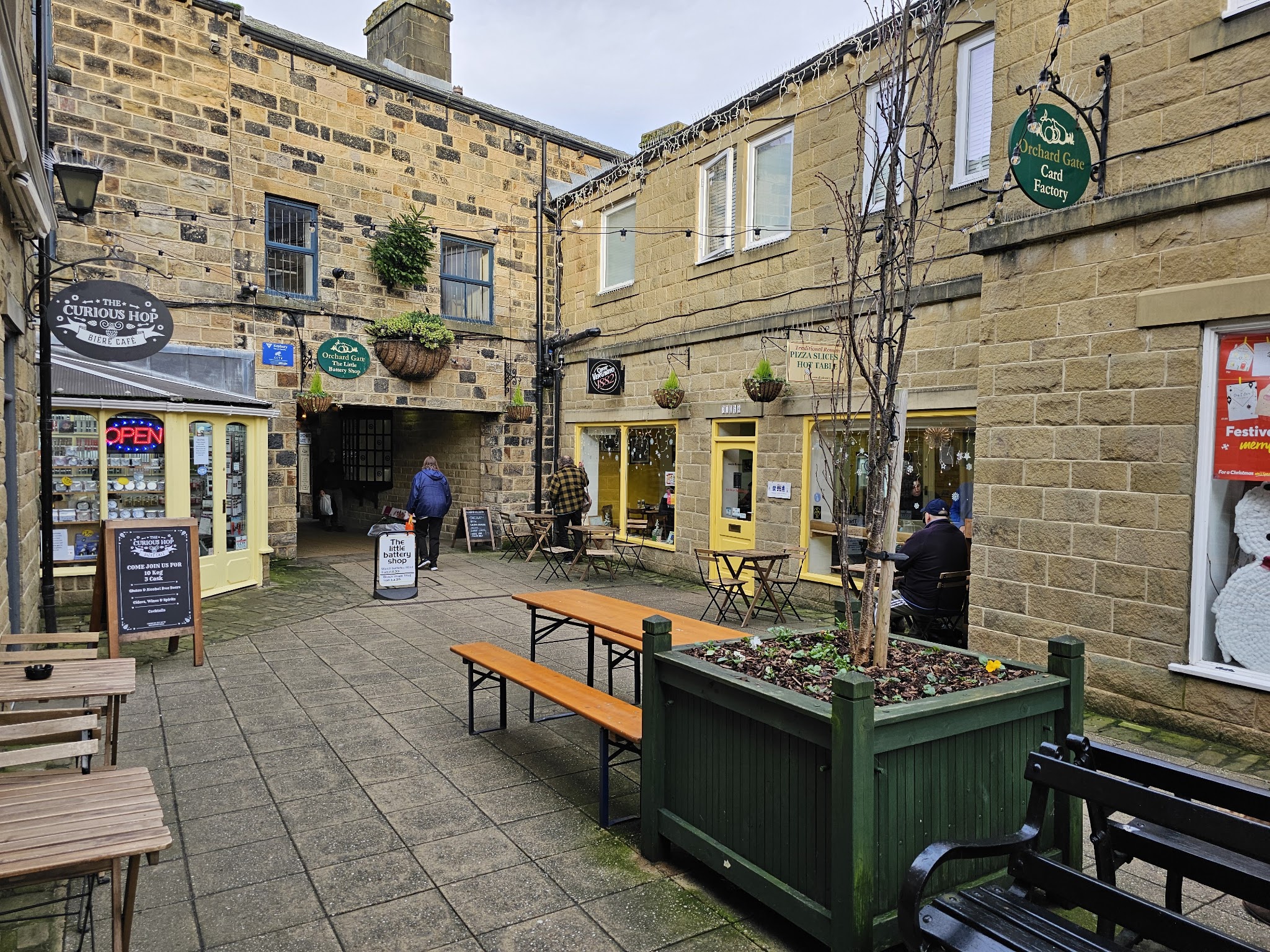 The yellow-fronted café and outdoor tables in the stone courtyard at Orchard Gate