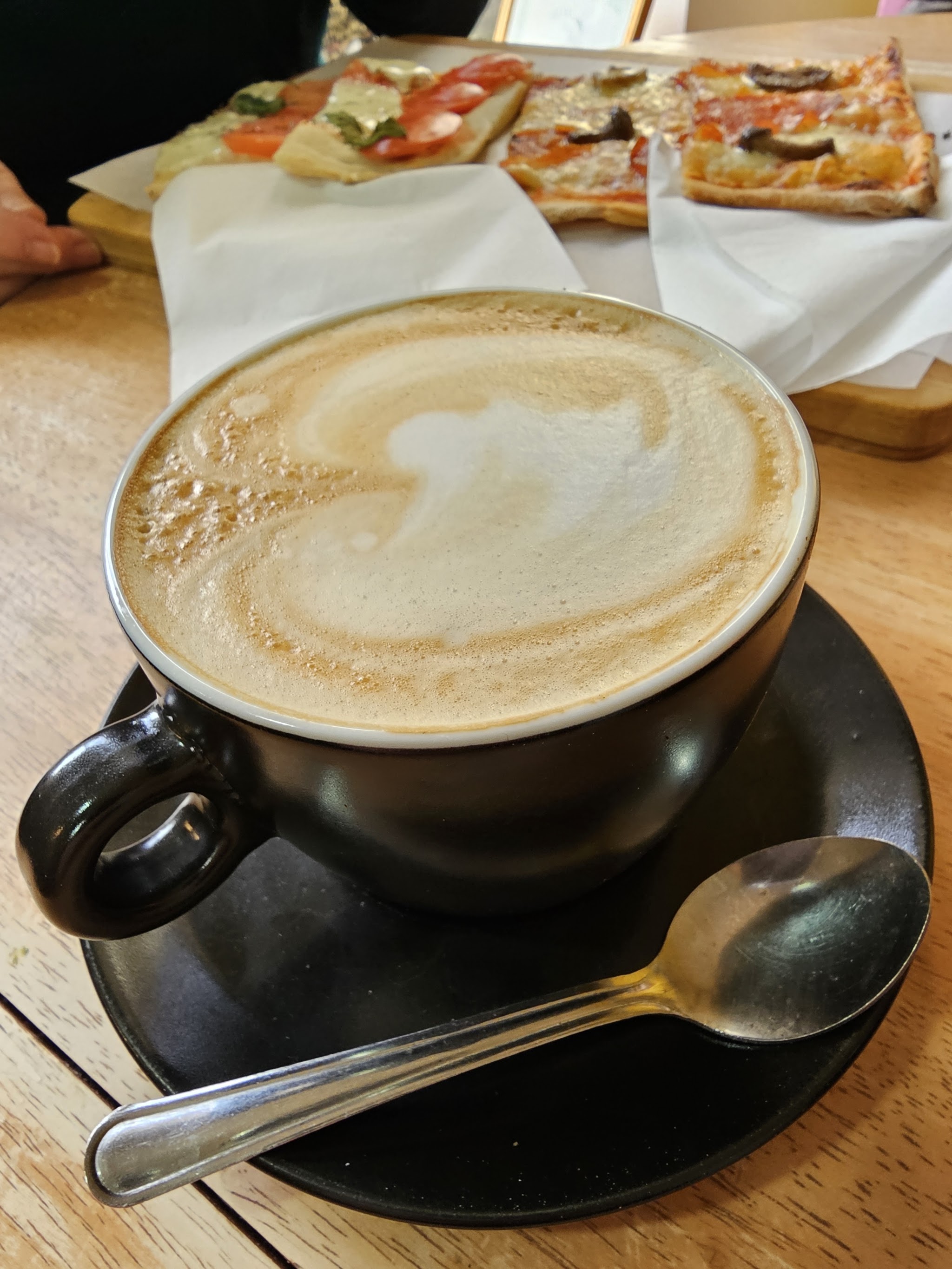 A cup of coffee with pizza slices at the café